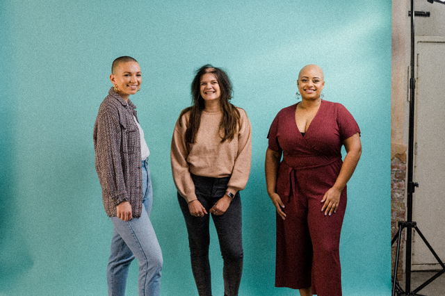 Three diverse women smiling against a turquoise backdrop, wearing casual and smart clothing