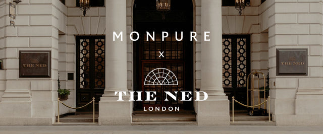 Elegant stone entrance of The Ned London hotel with black doors and gold signage