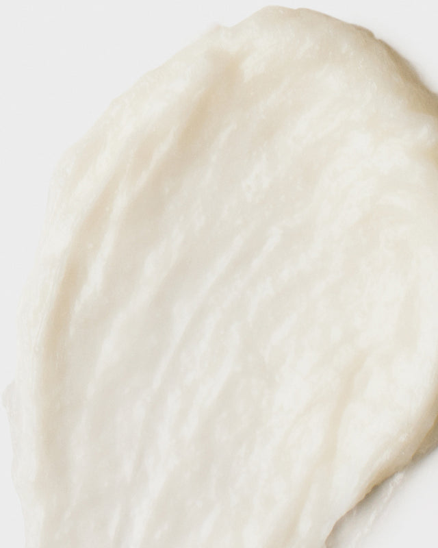 Creamy white scalp scrub texture with smooth, slightly whipped consistency on a white background
