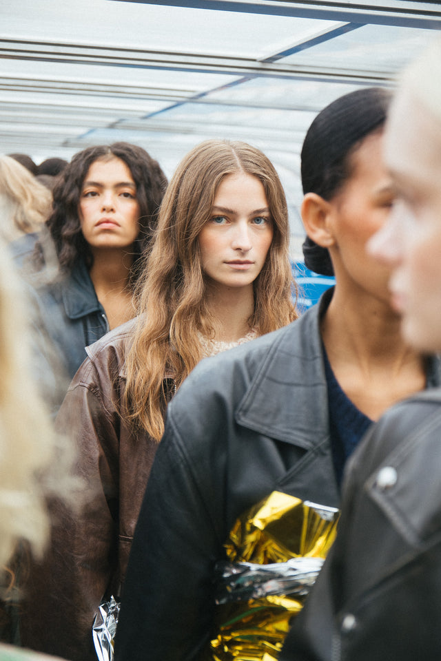 Models with diverse hairstyles wearing leather jackets at Copenhagen Fashion Week backstage