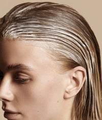 Close-up of person with wet hair coated in white creamy conditioner treatment