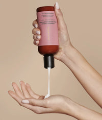Ceramide Complex Bond Repair Conditioner in brown bottle with pink label dispensing white cream into hand