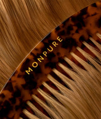 Close-up of luxury tortoiseshell comb with gold MONPURE branding on light brown hair