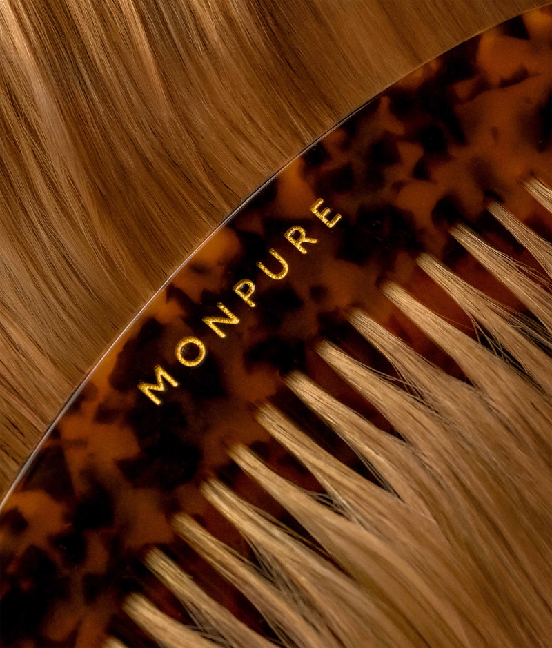 Close-up of luxury tortoiseshell comb with gold MONPURE branding on light brown hair