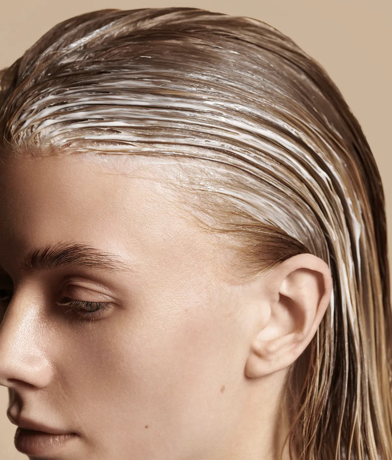Close-up of person with wet hair coated in white creamy conditioner treatment
