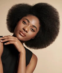 Woman with voluminous natural afro hair showcasing healthy, shiny hair likely from ceramide complex bond repair shampoo