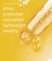 Close-up of clear golden hair oil with bubbles on a yellow background, promoting healthy hair benefits
