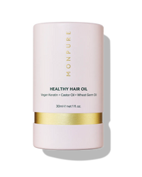 Pink cylindrical container of Monpure Healthy Hair Oil with gold band and black text