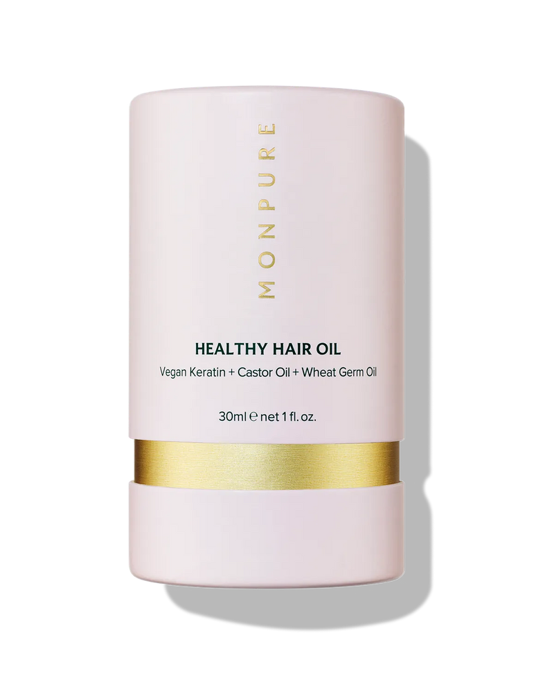 Pink cylindrical container of Monpure Healthy Hair Oil with gold band and black text
