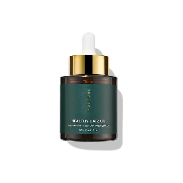 Small amber glass bottle of healthy hair oil with dark green label and gold dropper cap