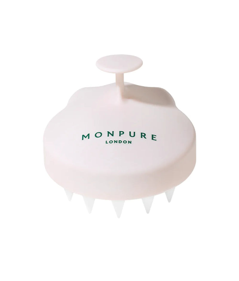 Pink plastic scalp massage brush with white silicone bristles and circular handle