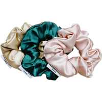 Trio of silk scrunchies in champagne gold, emerald green, and blush pink colours