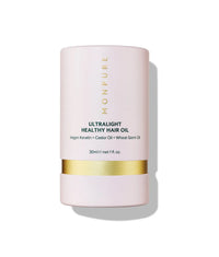 Pink cylindrical bottle of ultralight healthy hair oil with gold band and black text