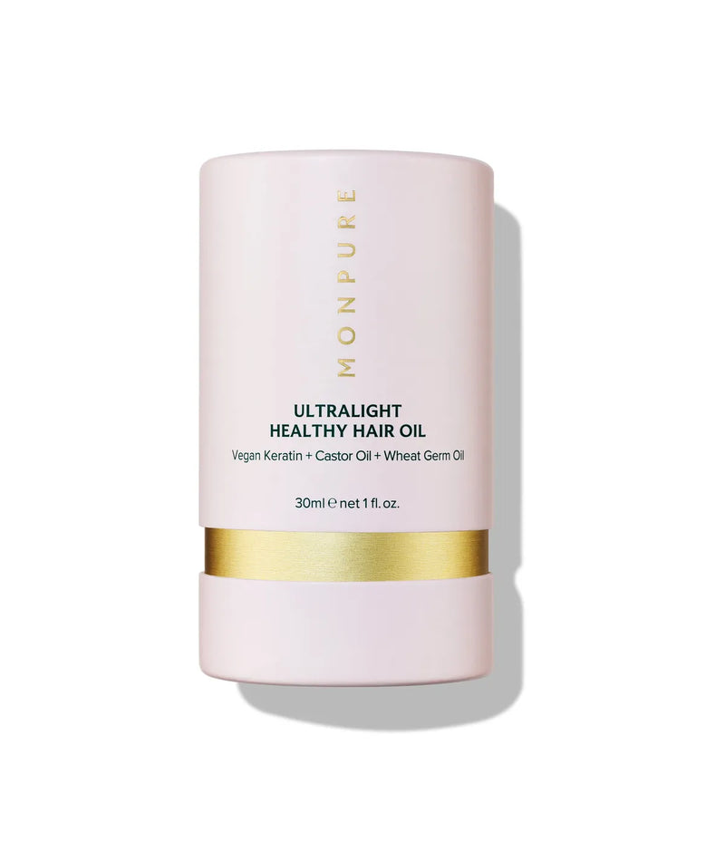 Pink cylindrical bottle of ultralight healthy hair oil with gold band and black text